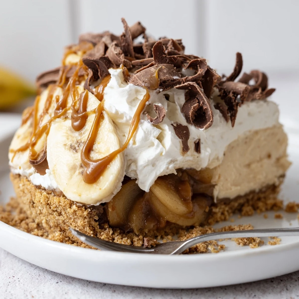 Richly layered banoffee pie featuring buttery caramel apples and a crunchy biscuit base.