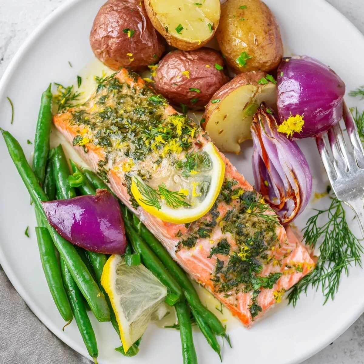 Lemon Herb Salmon & Potato Sheet Pan served with vibrant veggies and zesty lemon wedges.  