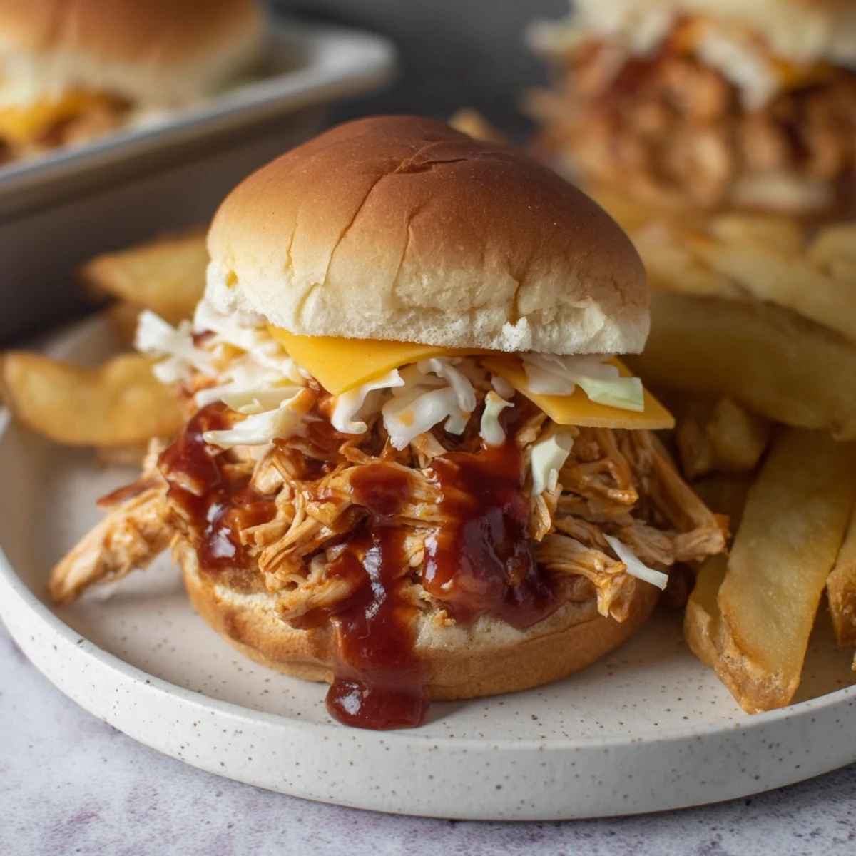 Warm BBQ chicken sliders with melted cheese, coleslaw, and a side of perfectly cooked french fries.