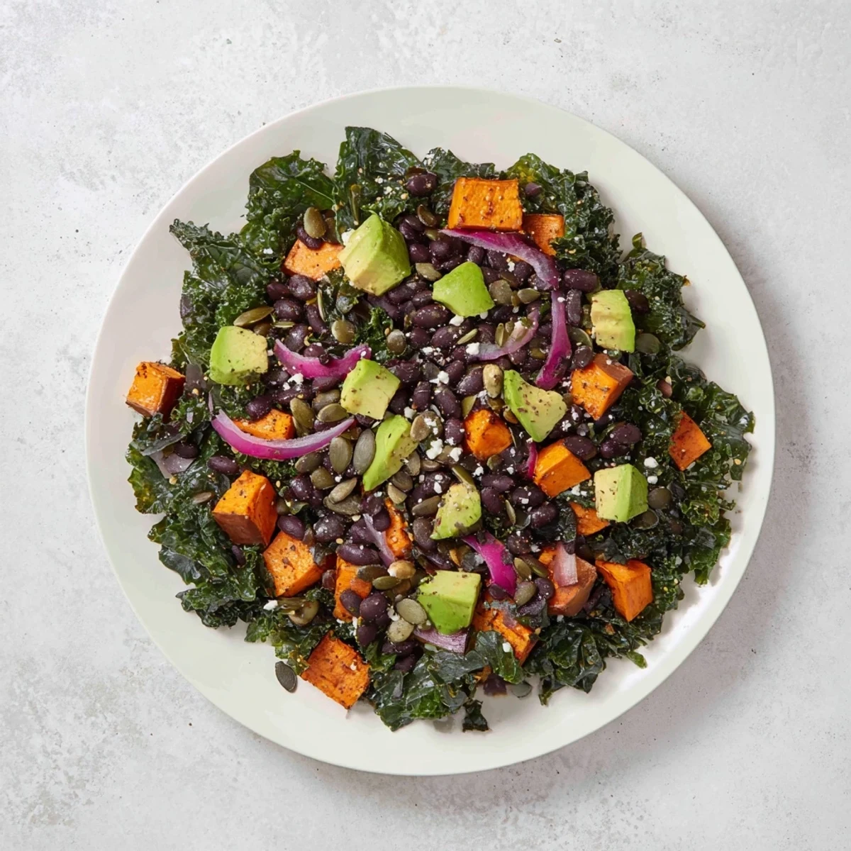 Vibrant massaged kale salad with roasted sweet potato, black beans, and a zesty lime dressing.