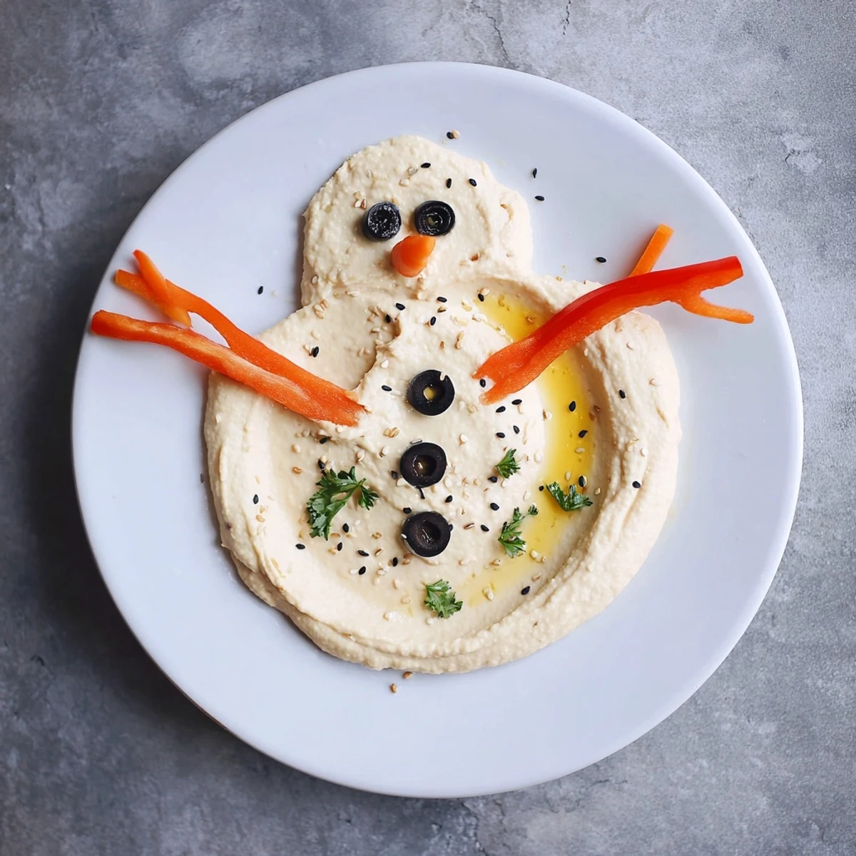 Vibrant melted snowman hummus platter: creamy hummus decorated with carrot, olives, and red pepper for a fun appetizer.