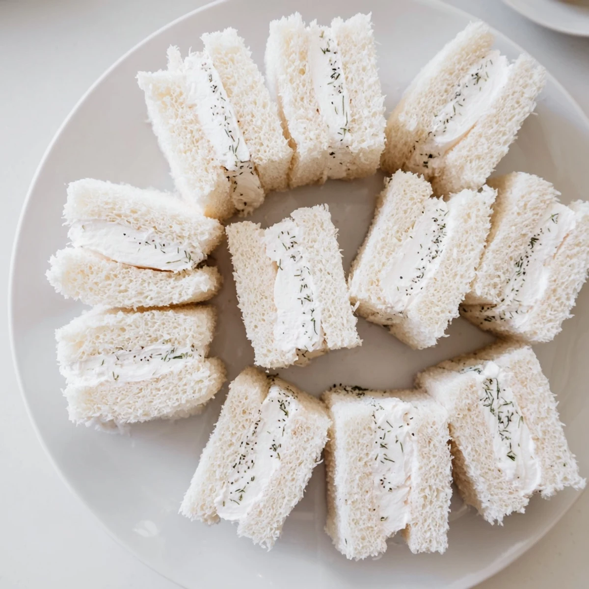 Delicate plate of Snowball Tea Sandwich Bites, coated in coconut, ready for a winter tea party.