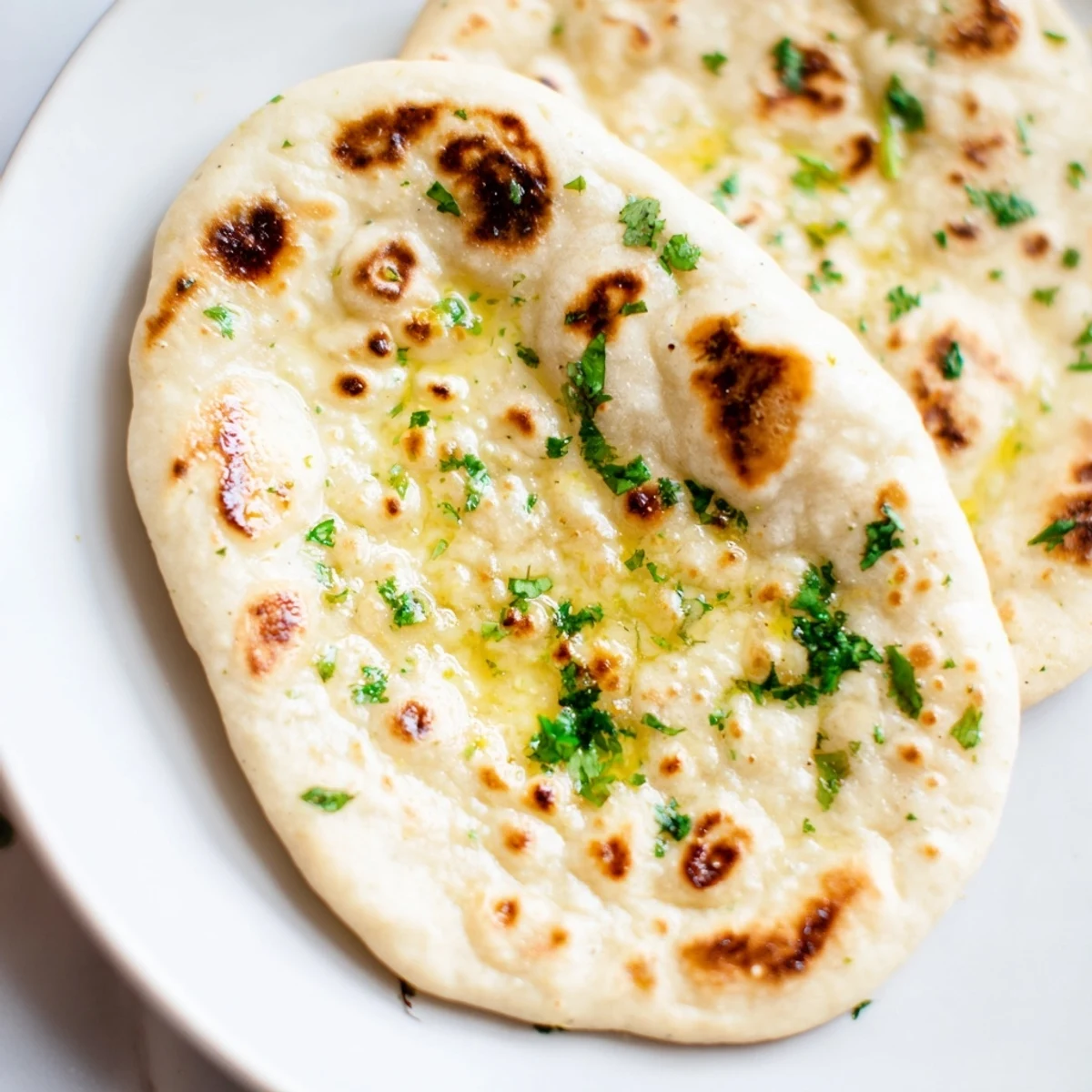 Fluffy, freshly made Homemade Garlic Naan Bread brushed with garlic butter and ready to eat.