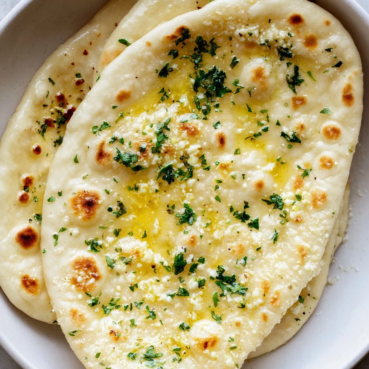 Golden-spotted Homemade Garlic Naan Bread, a savory Indian flatbread perfect for dipping into curry.