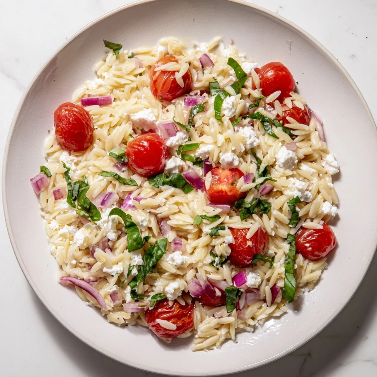 Vibrant Tomato Feta Orzo pasta salad with juicy tomatoes and creamy feta cheese, ready to enjoy.