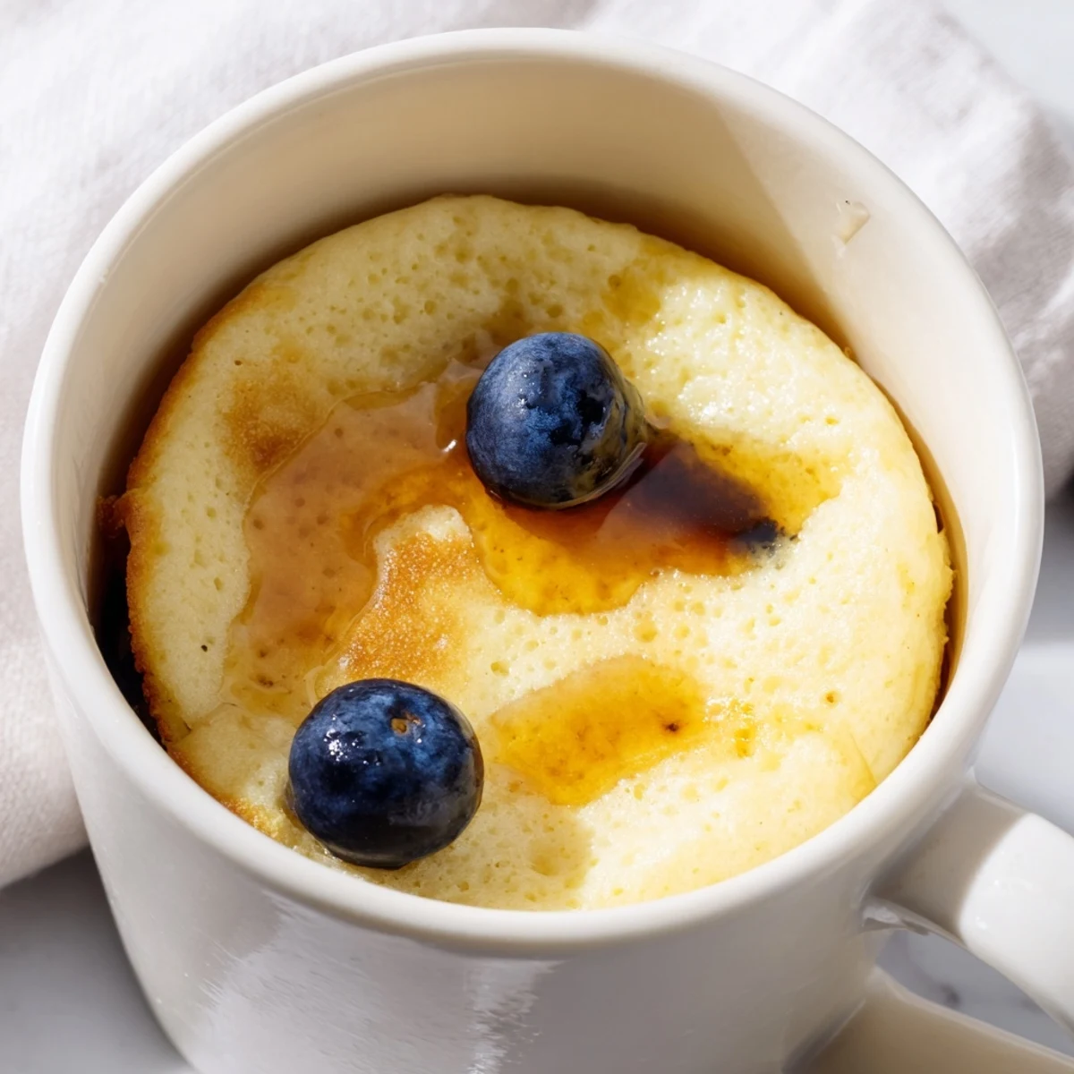 Golden, spongy Microwave Mug Pancakes drizzled with warm maple syrup, ready to eat.