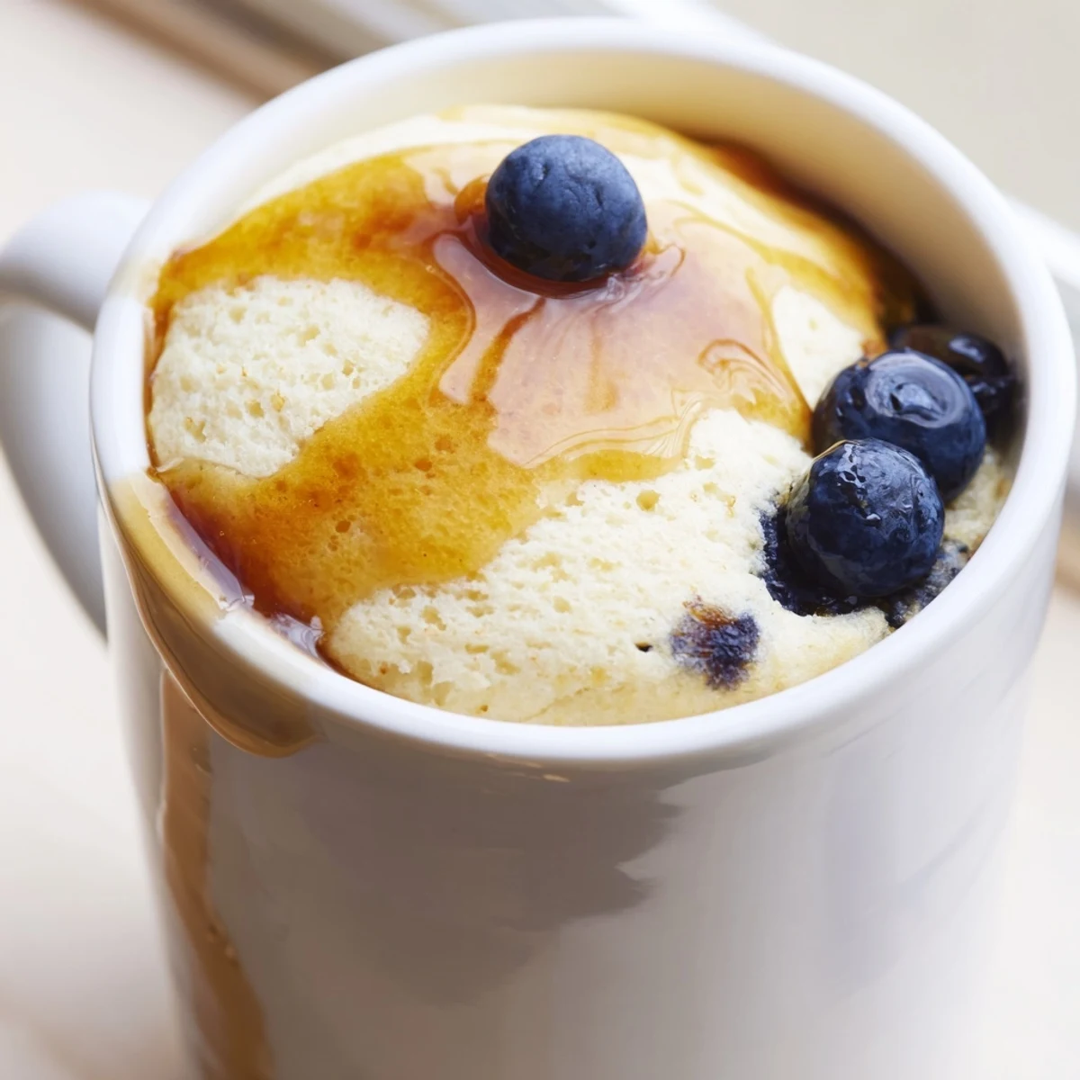 View of a single mug filled with light and fluffy Microwave Mug Pancakes, topped with berries.