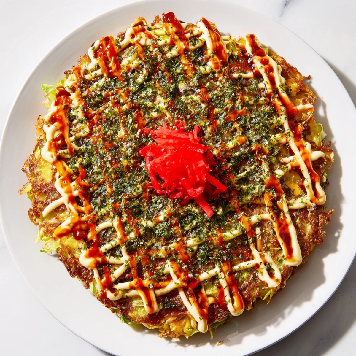 Golden Japanese Okonomiyaki Pancakes sizzle in a skillet, topped with creamy mayonnaise, tangy sauce, and dancing bonito flakes.