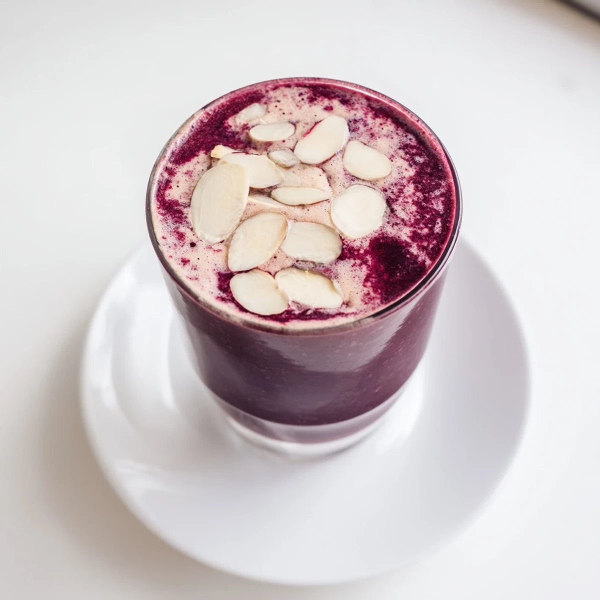 Close-up of Cherry Almond Smoothie in a glass, frosty and thick, garnished with a sliced banana and toasted almond slices.
