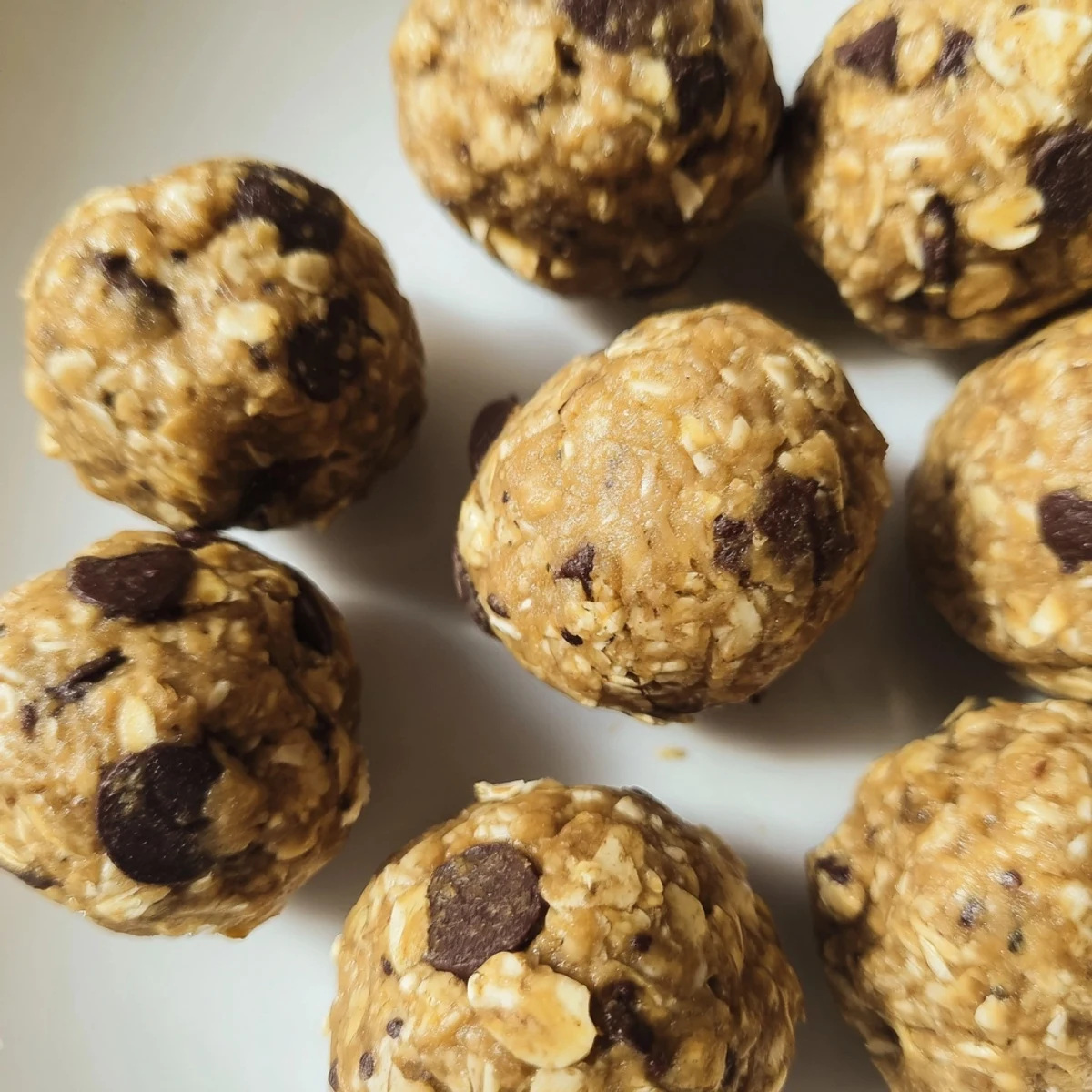 A close-up shot of Banana Chocolate Chip Energy Balls in a glass jar, revealing the chunky oats, flaxseed specks, and banana flecks perfect for snacking.