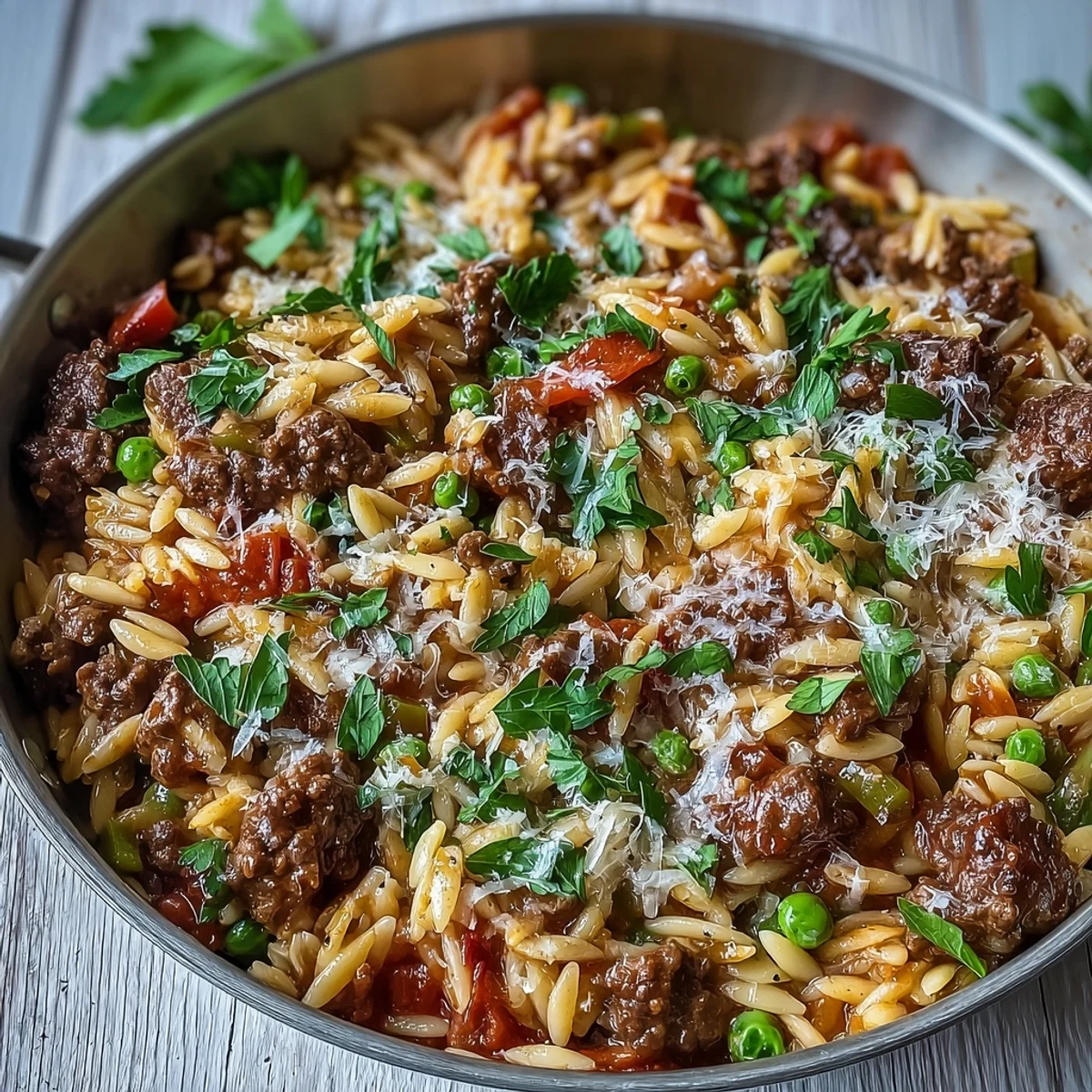 Serving suggestion of Comforting Ground Beef Orzo Dinner on a plate, garnished with parsley alongside a dinner roll.