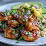 Bright mango salsa and nutty quinoa top these Fresh Shrimp and Creamy Avocado Bowls with Zesty Mango Salsa and Lime Chili Sauce, garnished with lime wedges.
