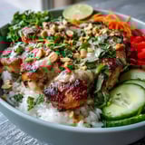 A vibrant Thai Peanut Chicken Bowl with fresh veggies, chopped peanuts, and cilantro, ready to enjoy alongside lime wedges.  