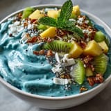 Creamy blue spirulina smoothie bowl artfully topped with exotic fruits and granola.