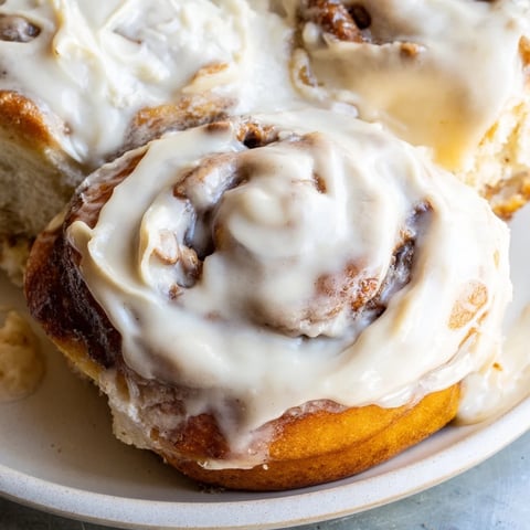 Fluffy Viral TikTok Heavy Cream Cinnamon Rolls glistening with icing, offering a sweet, warm aroma.