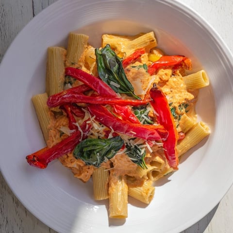 Creamy lightened-up vodka rosé Christmas pasta, showing a festive dish with vibrant red peppers and green spinach.