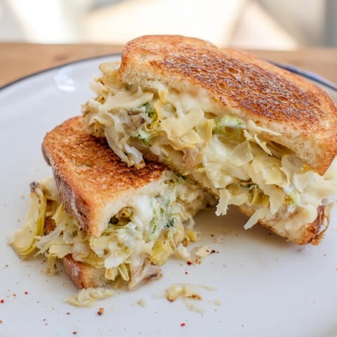 A close-up shot of a melty Air Fryer Spinach & Artichoke Dip Grilled Cheese sandwich with crispy bread.
