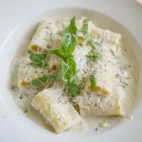 Creamy cottage cheese pasta swirls temptingly, plated and garnished with fresh basil for a bright flavor.