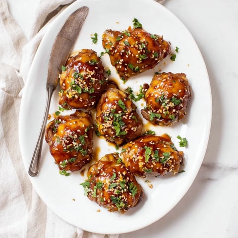 Juicy, bone-in chicken thighs glazed in sticky honey garlic sauce, garnished with fresh parsley and sesame seeds for dinner.