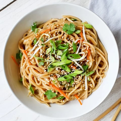 Steaming bowls of Asian Garlic Noodle Bowl garnished with green onions and sesame seeds.