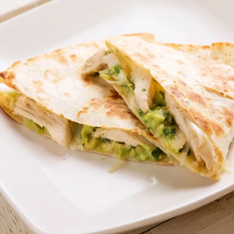 Golden-brown Chicken Avocado Quesadilla wedges stuffed with grilled chicken, creamy avocado mash, and melted cheese.