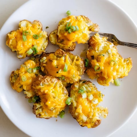 Crispy Smashed Green Onion Potato Bombs topped with melted cheese and herbs.  