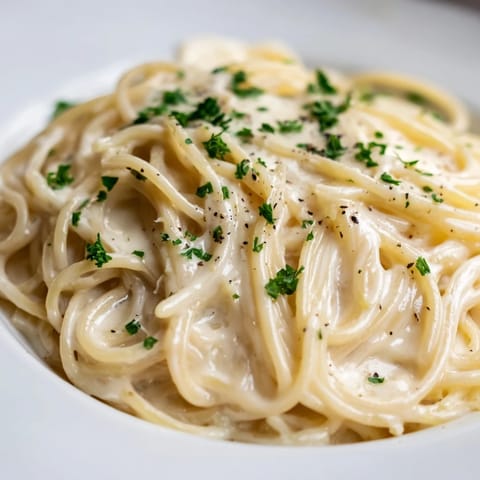A close-up shot of the Creamy Three-Cheese Spaghetti, perfectly coated in a smooth cheese sauce.