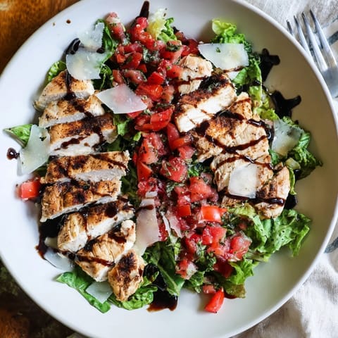 Freshly grilled chicken breast slices mingle with ripe tomatoes, red onion, and basil for a light Italian-American dinner.