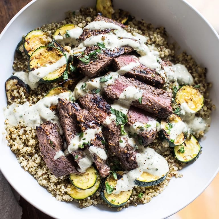 Deliciously layered Grilled Steak Bowl with Creamy Sauce & Grilled Zucchini garnished with garlic sauce.