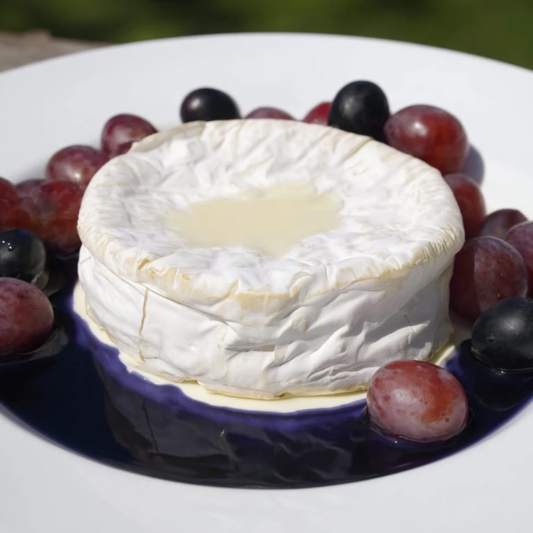 This stunning The Floating Island recipe features a vibrant blue yogurt sea, a cheese wheel island, and grapes.