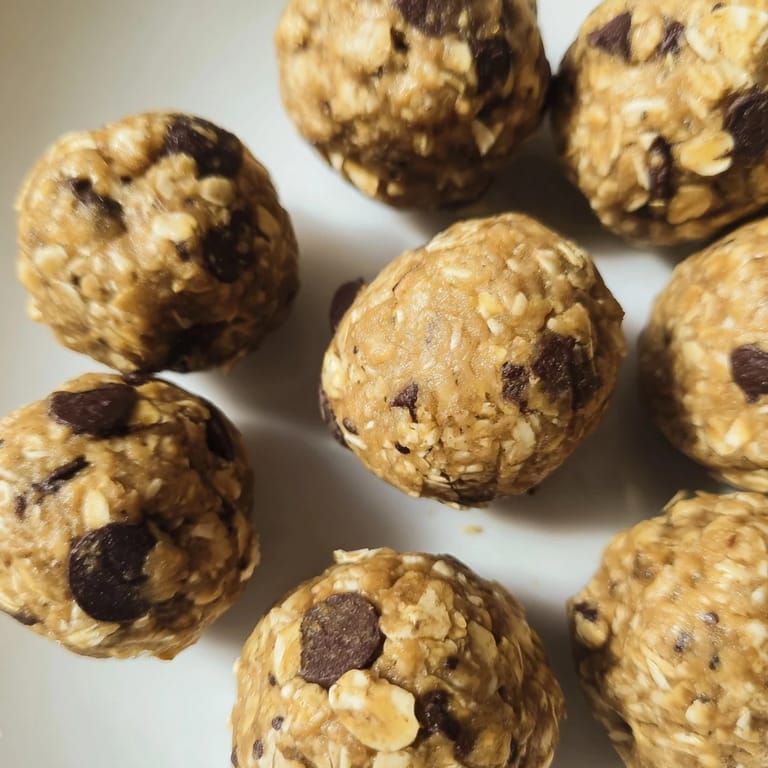 A close-up shot of Banana Chocolate Chip Energy Balls in a glass jar, revealing the chunky oats, flaxseed specks, and banana flecks perfect for snacking.